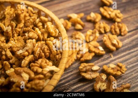 Noix pelées dans un panier en osier et noix pelées éparpillées sur une table en bois. Une alimentation saine. Régime de remise en forme. Gros plan Banque D'Images