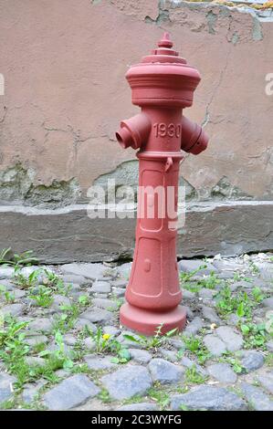 Borne d'eau rétro. Rouge. La rue est pavée de vieux pavés gris. Banque D'Images