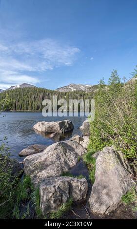 Lac Bear dans le parc national des montagnes Rocheuses Paysage photo avec de l'eau, des montagnes lointaines, des nuages et un fond forestier Banque D'Images