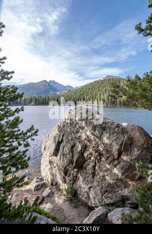 Lac Bear dans le parc national des montagnes Rocheuses Paysage photo avec de l'eau, des montagnes lointaines, des nuages et un fond forestier Banque D'Images