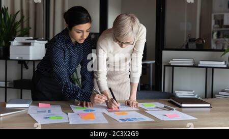 Femmes d'affaires multiraciales travaillant sur les statistiques de projet au bureau Banque D'Images