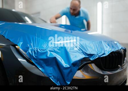 Emballage de voiture, homme installe le film de protection en vinyle Banque D'Images