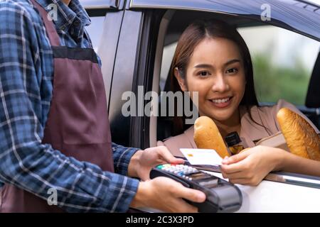 Portrait de femme asiatique faire le paiement mobile sans contact technologie pour la commande d'épicerie en ligne et le service de drive. Conduire et de la nourriture en ligne i Banque D'Images