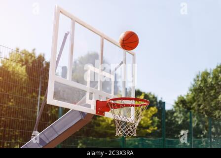 Ballon de basket-ball traversant le panier dans l'arène de sport en plein air, espace vide Banque D'Images