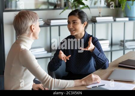 Collègues multiraciaux qui parlent tout en travaillant sur un projet commun au bureau Banque D'Images