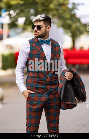 Jeune homme élégant dans une chemise blanche tient une veste de costume sur sa main alkink dans la rue Banque D'Images
