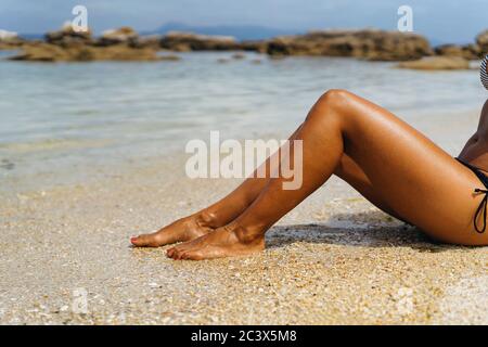 Femme bronzée jambes sur le rivage de paradis plage vide Banque D'Images