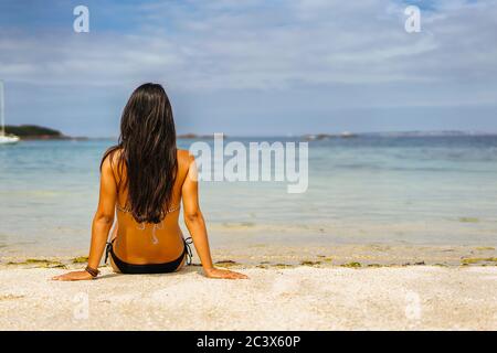 Vue arrière de la femme bronzée relaxante sur le rivage de la plage Banque D'Images