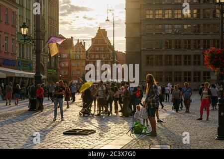 Wroclaw, Pologne - 16 août 2019 : musicien de rue jouant de la guitare devant les gens sur la place du marché dans la vieille ville au coucher du soleil. Banque D'Images