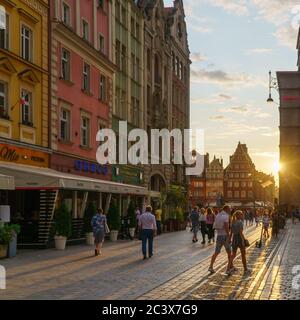 Wroclaw, Pologne - 16 août 2019 : personnes marchant le long de la place du marché de la ville dans la vieille ville au coucher du soleil. Banque D'Images