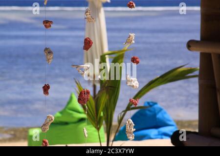 Décorations de morceaux de corail rouge et blanc, accrochée au fil de fil au bar de plage exotique, avec parapluie flou et vagues de mer en arrière-plan, sur Gili Air isl Banque D'Images