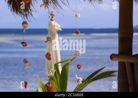 Décorations de morceaux de corail rouge et blanc, accrochée au fil de fil au bar de plage exotique, avec parapluie flou et vagues de mer en arrière-plan, sur Gili Air isl Banque D'Images