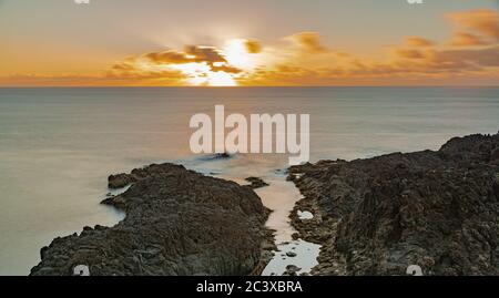 Coucher de soleil sur l'horizon océanique atlantique, avec formation de roches volcaniques, longue exposition, Rojas, El Sauzal, Tenerife, îles Canaries, Espagne Banque D'Images