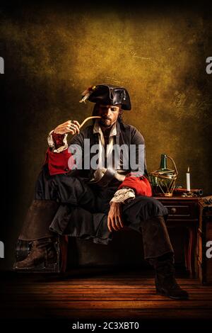 Portrait d'un pirate fumant un tuyau, assis dans une taverne Banque D'Images