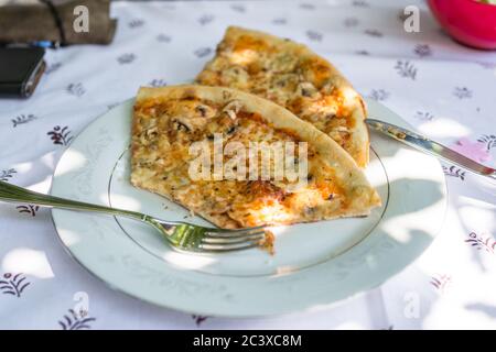 Morceaux de pizza sur une assiette sur une table avec nappe et couverts, Allemagne Banque D'Images