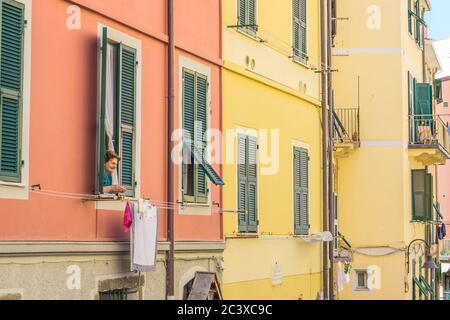 Femme italienne âgée, vue par sa fenêtre sur la rue en dessous. Lavage suspendu à une ligne de lavage. Prise en été Banque D'Images