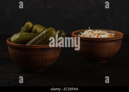 Cornichons et choucroute dans un bol en argile sur fond de béton foncé Banque D'Images