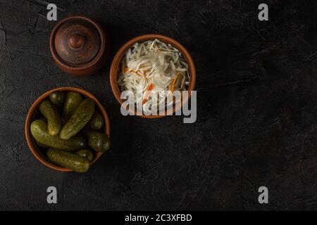 Cornichons et choucroute dans un bol en argile sur fond de béton foncé Banque D'Images