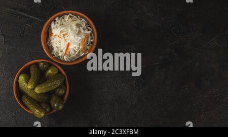 Cornichons et choucroute dans un bol en argile sur fond de béton foncé Banque D'Images