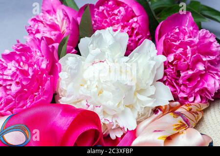 Bouquet de pivoines blanc et fuchsia sur le foulard en soie de femme isolé sur fond lilas. Gros plan, plat. Banque D'Images