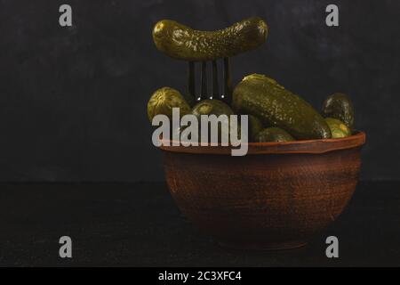 Cornichons et choucroute dans un bol en argile sur fond de béton foncé Banque D'Images