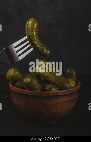 Cornichons et choucroute dans un bol en argile sur fond de béton foncé Banque D'Images