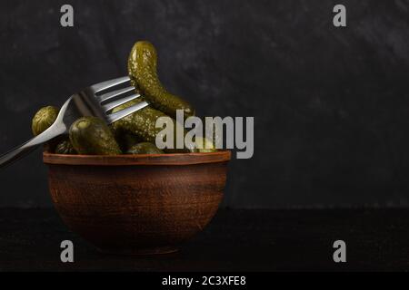 Cornichons et choucroute dans un bol en argile sur fond de béton foncé Banque D'Images