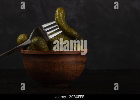 Cornichons et choucroute dans un bol en argile sur fond de béton foncé Banque D'Images