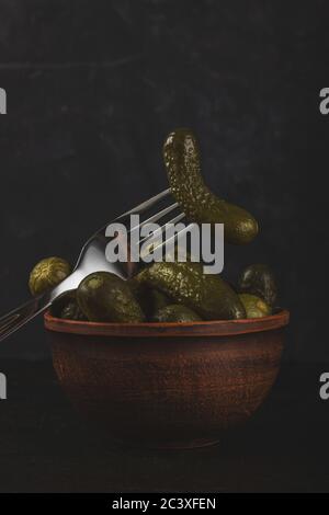 Cornichons et choucroute dans un bol en argile sur fond de béton foncé Banque D'Images