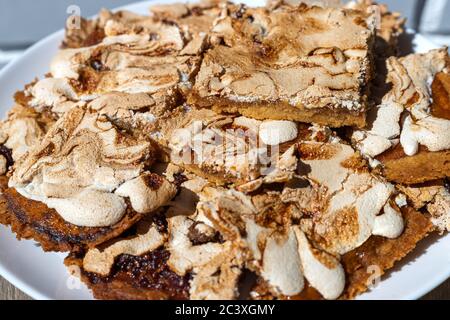 Gros plan de morceaux oblongs de gâteau maison à la crumble avec confiture de fraise recouverte de meringue servi sur une table en bois. Streuselkuchen gâteau, vue de dessus, je Banque D'Images