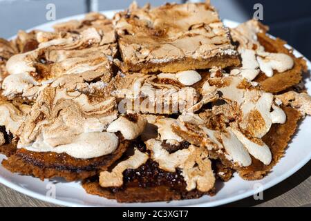 Gros plan de morceaux oblongs de gâteau maison à la crumble avec confiture de fraise recouverte de meringue servi sur une table en bois. Streuselkuchen, idée de pâtisserie Banque D'Images