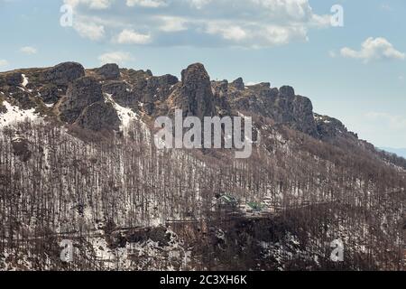 Colonnes de montagne impressionnantes, pointues, rocailleuses, arbres sans feuilles, reste de la neige sur le sol et ciel bleu avec des nuages blancs Banque D'Images
