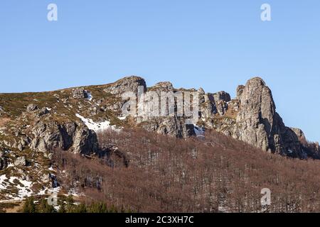 Colonnes de montagne impressionnantes, pointues, rocailleuses, arbres sans feuilles, reste de la neige sur le sol et ciel bleu avec des nuages blancs Banque D'Images