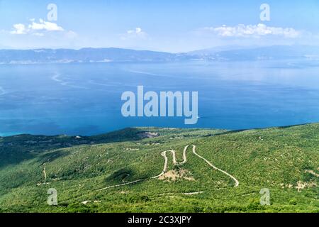 Montagnes de Galichica. Vue d'en haut sur le lac d'Ohrid et la route sinueuse avec les montagnes en arrière-plan et le ciel bleu. Macédoine du Nord, Europe. Banque D'Images