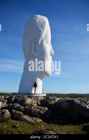 Une femme se trouve à côté d'une sculpture surdimensionnée de Jaume Plensa, au PARC PILANE SKULPTURE, Tjörn, Suède. Banque D'Images