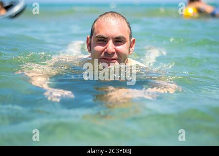 Homme natation dans la mer bleu azur. Banque D'Images