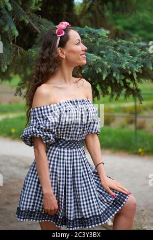 belle fille aux cheveux bouclés avec un sourire sur son visage Dans une robe d'été près de l'arbre de Noël dans le Stationnement Banque D'Images