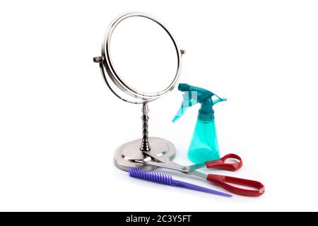 un miroir de table rond et des outils de coupe des cheveux, un pulvérisateur, des ciseaux et des peignes isolés sur blanc Banque D'Images