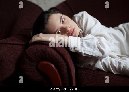 Portrait of young woman lying on sofa Banque D'Images