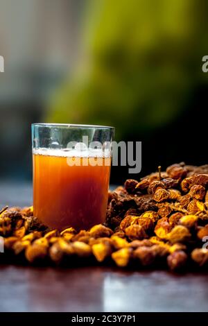 Gros plan de la soapnut fraîche brute sur la surface brune avec sa solution ou son liquide dans un verre le long de celle-ci. Banque D'Images