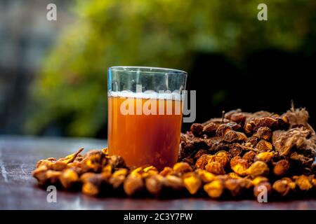 Gros plan de la soapnut fraîche brute sur la surface brune avec sa solution ou son liquide dans un verre le long de celle-ci. Banque D'Images