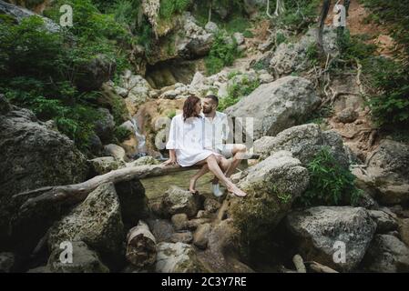 Ukraine, Crimée, Jeune couple assis sur la branche au-dessus de la rivière dans le canyon Banque D'Images