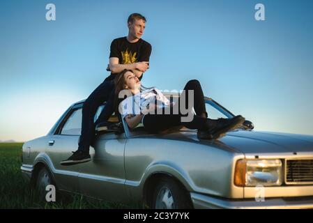 Ukraine, Crimée, couple assis sur une vieille voiture dans un paysage rural Banque D'Images