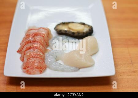 Ingrédients de cuisine de fruits de mer frais crus sur une assiette blanche. Homard pelé, crevettes, crevettes et ormeaux prêts à cuire. Banque D'Images