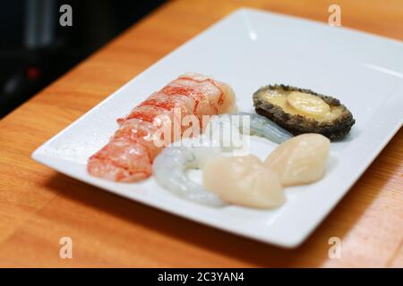 Homard pelé, crevettes, crevettes et ormeaux sur une table en bois. Ingrédients de cuisine de fruits de mer frais crus prêts à cuire Banque D'Images