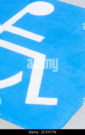 Gros plan de blanc sur bleu pour handicapés sur le panneau et le symbole pour fauteuil roulant sur le parking pour handicapés Banque D'Images