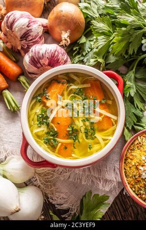 Bouillon de poulet dans un bol vintage avec nouilles maison oignon carottes céleri herbes ail et légumes frais. Banque D'Images