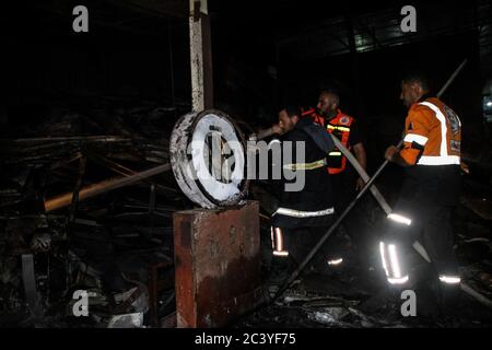 22 juin 2020 : Gaza, Palestine. 22 juin 2020. Les équipes palestiniennes de la Défense civile travaillent pour éteindre un incendie qui a éclaté dans une installation industrielle à l'est du camp de réfugiés de Jabalia. Le personnel du service de secours a eu du mal à contenir et à mettre le feu, ce qui a causé une destruction grave de l'usine. Le bâtiment brûlé est situé près des bureaux de l'Administration civile dans le nord de la bande de Gaza crédit: Ahmad Haaballah/IMAGESLIVE/ZUMA Wire/Alamy Live News Banque D'Images