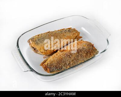 Deux carcasses d'un poisson sans tête frits en panure se trouvent dans un bol en verre sur fond blanc. Vue latérale, mise au point sélective Banque D'Images