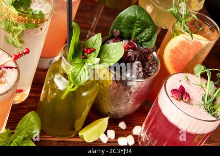 Cocktails colorés dans différents verres sur une table en bois Banque D'Images